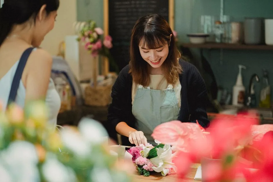 People arranging flowers at a long workshop bench