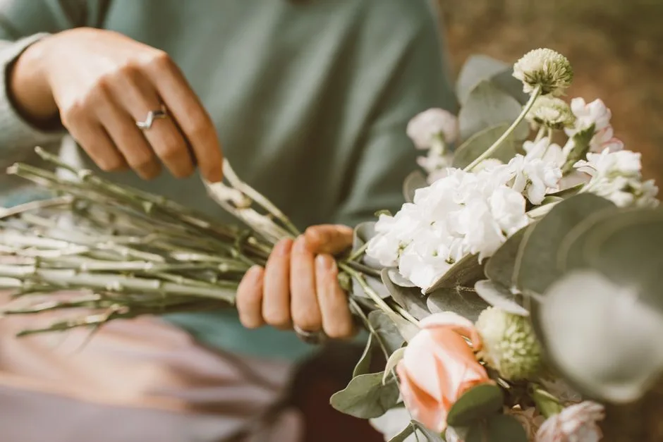 Hands wiring a boutonnière at a studio bench